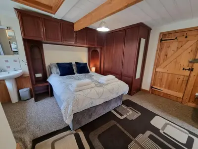 a bedroom with a bed and a bathroom with a sink at Cringoed House in Aberaeron