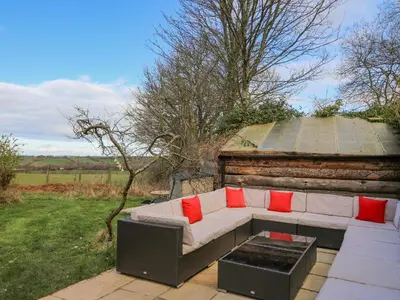 a white couch with red pillows sitting on a patio at Cringoed House in Aberaeron