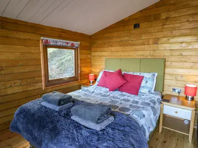 a bedroom with a bed in a log cabin at Tree House in Aberaeron