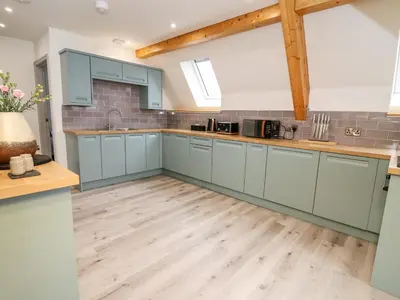 a kitchen with blue cabinets and a wooden floor at Brecknock Cheviot - The Sheepfold in Llandrindod Wells