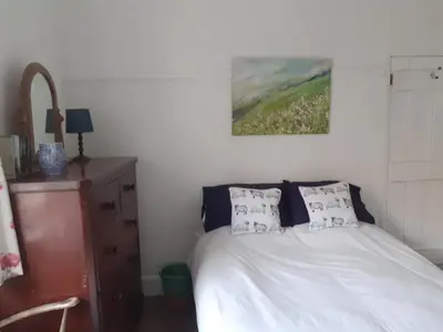 a bedroom with a bed and a painting on the wall at Robert's Cottage in Abergynolwyn