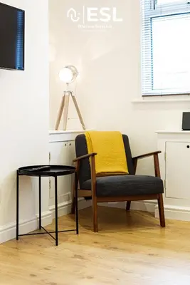 a chair with a yellow blanket sitting next to a table at 2 Bedroom Terrace Cottage, Parking, 5 minutes drive to Royal Shrewsbury Hospital in Shrewsbury