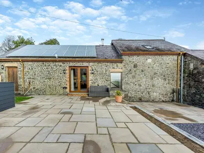 a stone house with solar panels on the roof at Bwlchygwynt in Rhandirmwyn