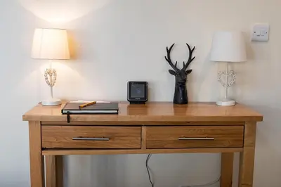 a wooden desk with two lamps and a clock on it at The Barn in Bala