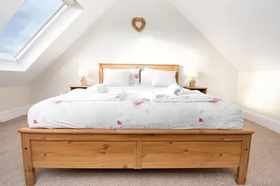 a bedroom with a large bed with white sheets at The Barn in Bala