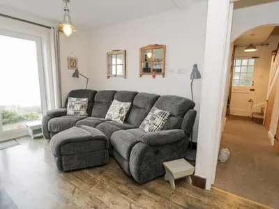 a living room with a gray couch and a window at Sibrwd Y Mor in Harlech