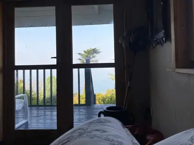 a bedroom with a door open to a porch with a palm tree at Sibrwd Y Mor in Harlech