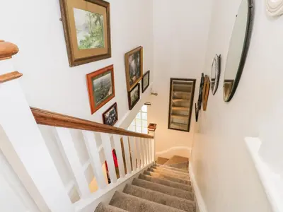 a hallway with stairs with paintings on the wall at Sibrwd Y Mor in Harlech