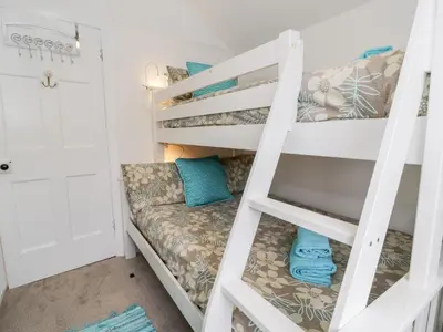 a bunk bed in a tiny room with a couch on the bottom bunk at Sibrwd Y Mor in Harlech