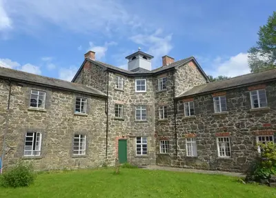 an old stone building with a tower on top of it at Llanfyllin Workhouse - Y Dolydd in Llanfyllin