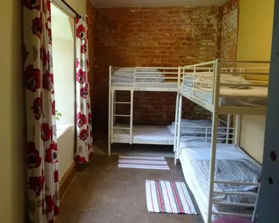 a room with two bunk beds and a brick wall at Llanfyllin Workhouse - Y Dolydd in Llanfyllin