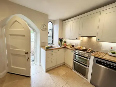 a kitchen with white cabinets and an open door at Trillow House, Clungunford, Ludlow in Clungunford