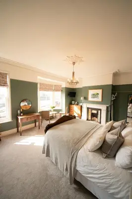 a bedroom with a large bed and a fireplace at Riversdale House Bed & Breakfast in Llangollen