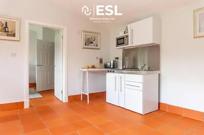 a kitchen with white cabinets and a orange tile floor at Quarry View Garden Studio in Shrewsbury with Parking in Shrewsbury