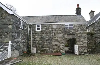 an old stone house with a stone wall at Romantic Hideaway in Trawsfynydd
