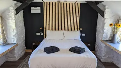 a bedroom with a large white bed with two bags on it at Romantic Hideaway in Trawsfynydd