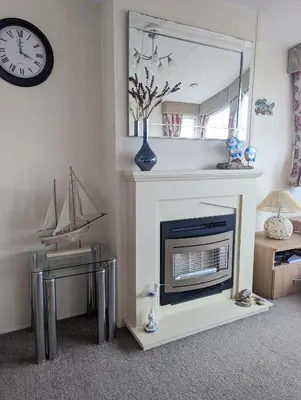 a living room with a fireplace and a mirror at Peacehaven, Ynyslas, Borth in Borth