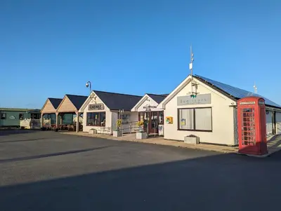 a red phone booth in front of a building at Peacehaven, Ynyslas, Borth in Borth