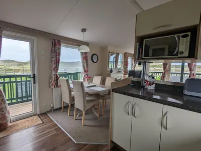 a kitchen and dining room with a table with a microwave at Peacehaven, Ynyslas, Borth in Borth