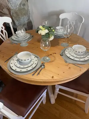 a wooden table with plates and wine glasses on it at Trawsfynydd Stone Cottage in Trawsfynydd