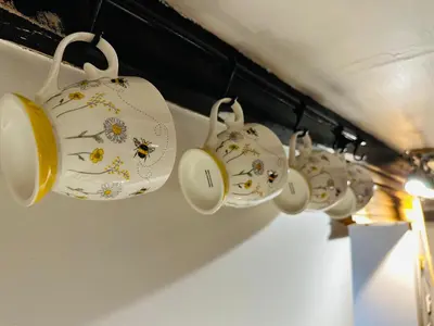 a row of tea cups hanging from a wall at Trawsfynydd Stone Cottage in Trawsfynydd