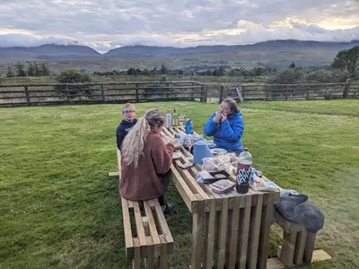 a group of people sitting at a picnic table at Grade II Lodge House 2 Bedroom in Trawsfynydd