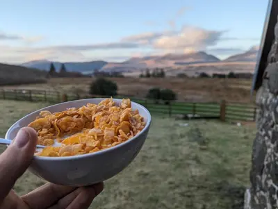 a person holding a bowl of food in a field at Grade II Lodge House 2 Bedroom in Trawsfynydd