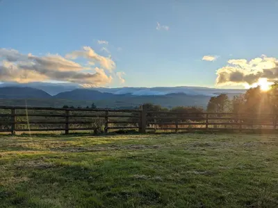 a fence in a field with the sunset in the background at Grade II Lodge House 2 Bedroom in Trawsfynydd