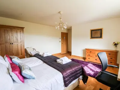 a bedroom with a large bed and a chair at The Orchard in Knighton