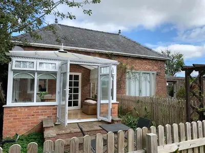 a greenhouse in the front of a brick house at The Little Coach House in Wales in Newtown