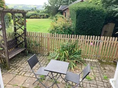 a patio with two chairs and a table and a fence at The Little Coach House in Wales in Newtown