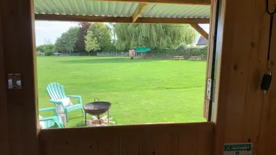 a window view of a yard with two chairs and a grill at Willowdene shepherds hut in Oswestry