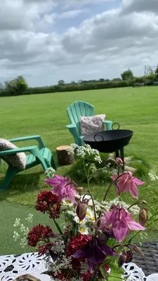 a table and chairs and flowers on a field at Willowdene shepherds hut in Oswestry