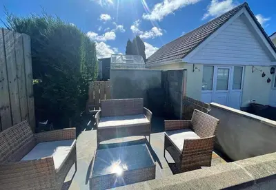 a patio with wicker chairs and a glass table at Y Villa Môr in Llanarth