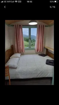 a bedroom with a large bed with a window at Shepherds hut Lowri in Dolgellau