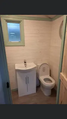 a bathroom with a sink and a toilet and a window at Shepherds hut Lowri in Dolgellau