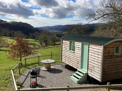 a small cabin with a table and a fence at Shepherds hut Lowri in Dolgellau
