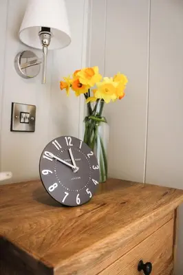 a clock sitting on top of a dresser with flowers at Fawns Rest in Nantmel