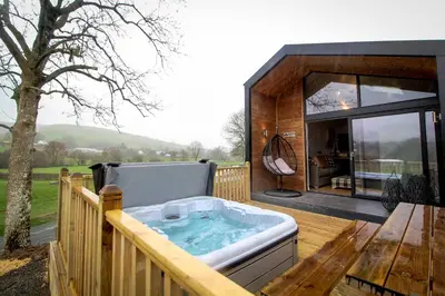 a hot tub on the deck of a house at Buck Barn in Nantmel