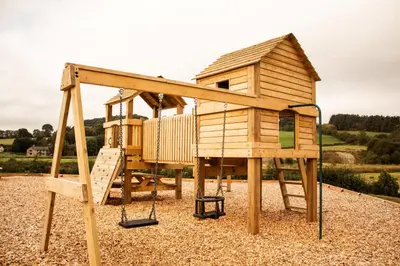 a wooden play house with a swing at Mayflower in Rhayader