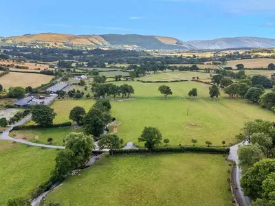 an aerial view of a green field with mountains in the background at Doe Lodge in Rhayader