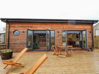 a house with chairs and a table on a deck at Tin Shed in Rhayader