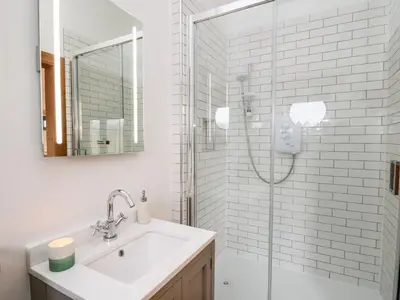 a white bathroom with a sink and a shower at Tin Shed in Rhayader