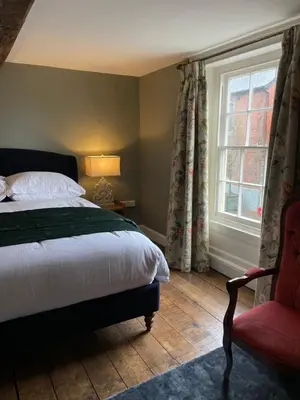 a bedroom with a bed and a chair and a window at Hurdley House-Georgian Town House in Montgomery