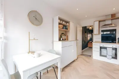 a kitchen with a white table and a clock on the wall at Quaint Georgian house with Parking & Huge Garden 10 mins walk from town in Shrewsbury