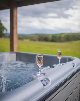 two glasses of wine sitting in a hot tub at Romantic country cabin with log burner, spectacular views, spa hot tub - Brecon Beacons National Park dog friendly in Llangadog