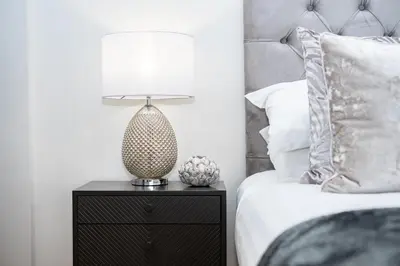 a lamp on a night stand next to a bed at The Old Glassworks by Bevolve in Shrewsbury