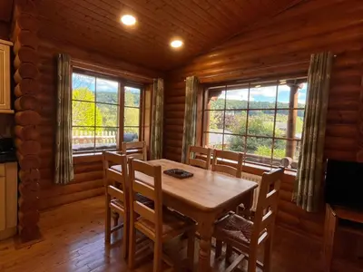 a dining room with a table and chairs and windows at Countryside 3 Bedroom Log Cabin With Private Hot Tub - Ash in Leominster