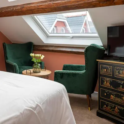 a bedroom with two green chairs and a skylight at The Fanny Talbot in Barmouth