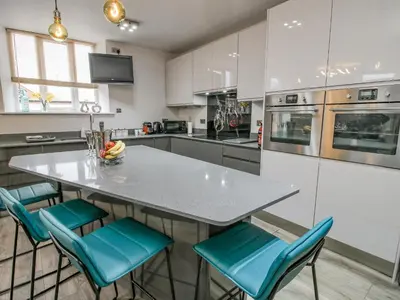 a kitchen with a table and blue chairs at Wesleyan House in Oswestry